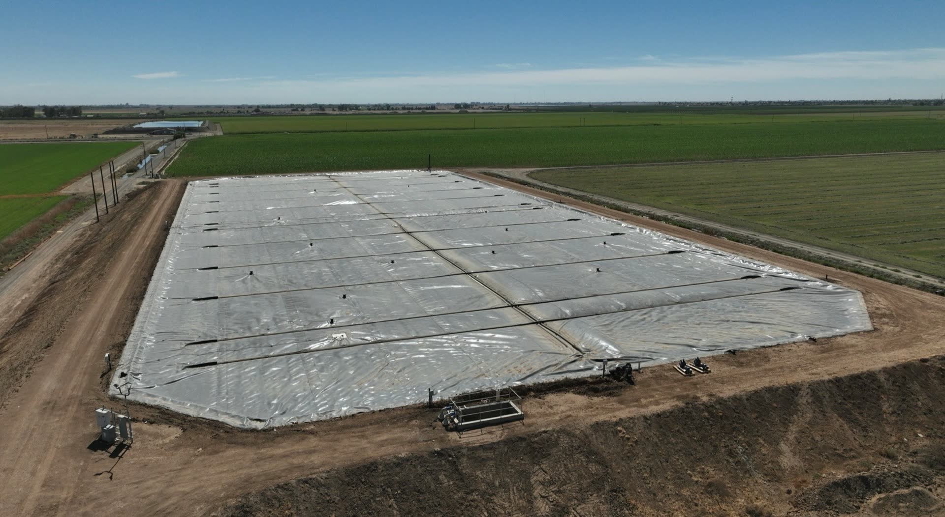 A covered lagoon digester between the fields — where the negative number starts.